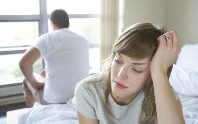 Couple sitting on bed discussing reasons for cheating