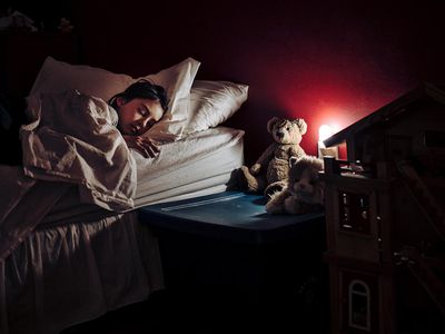 Girl asleep in bed lit only by night light.