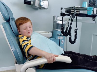 Scared child gripping the arms of chair in a dentist's office