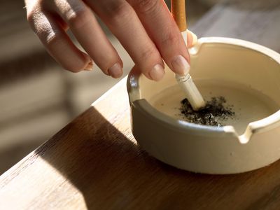 Hand holding cigarette in ashtray