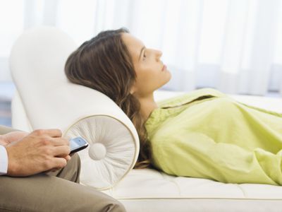 Psychiatrist holding a mobile phone with a patient lying on the bed