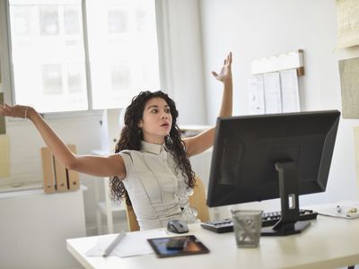 Angry woman sitting at her desk with hands in the air