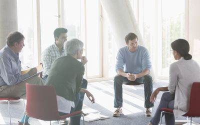 group of men and women talking in a circle of chairs