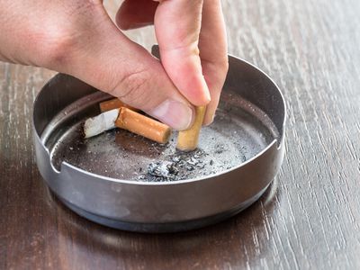 a person putting a cigarette out in an ashtray