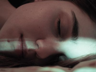 Close-Up Of Young Woman Sleeping On Bed At Home