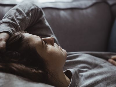 Close-up of sad woman lying on sofa at home 