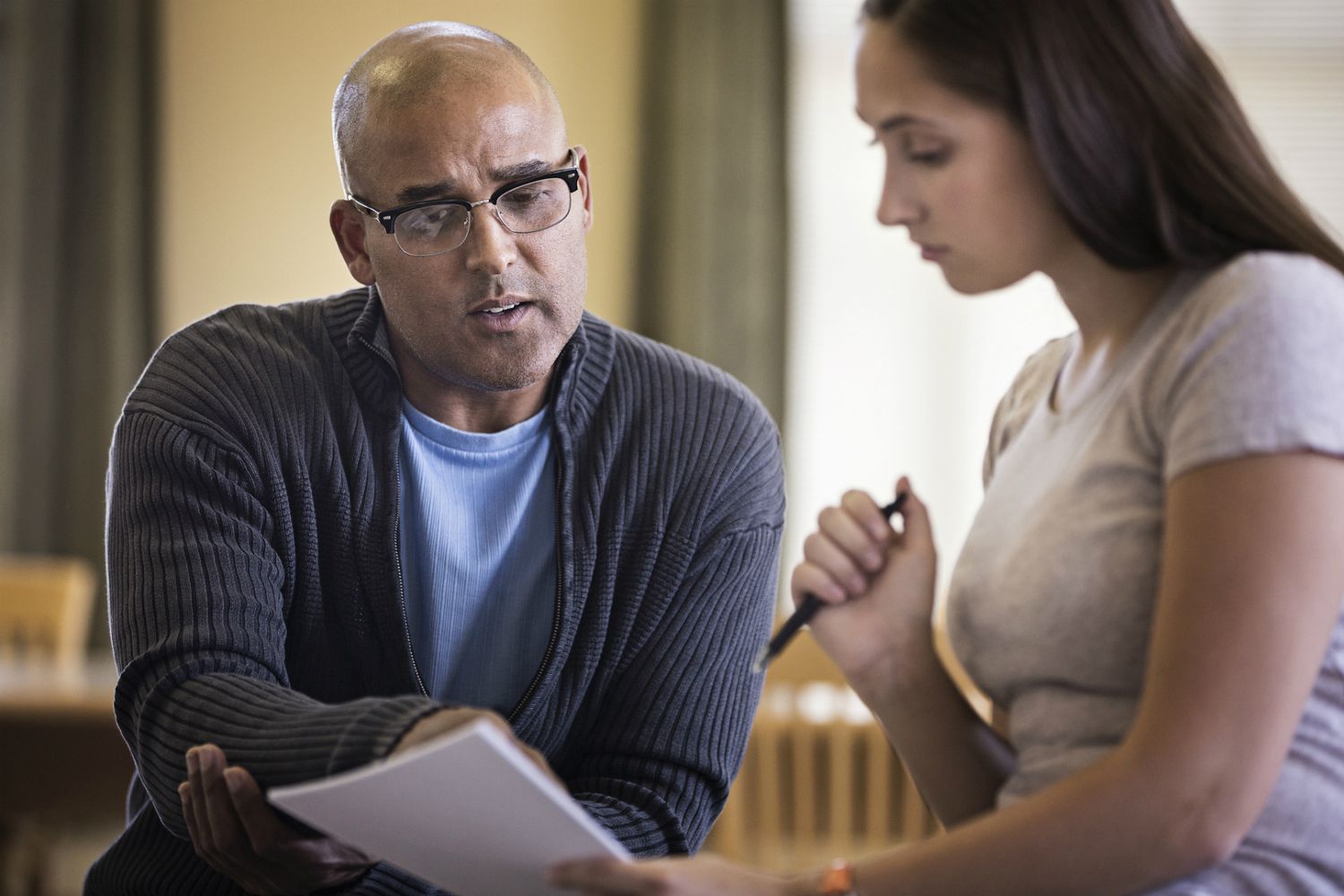 Male life coach talking to young woman and pointing to paperwork