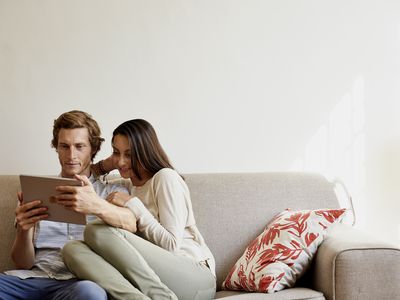 Couple using digital tablet on sofa at home