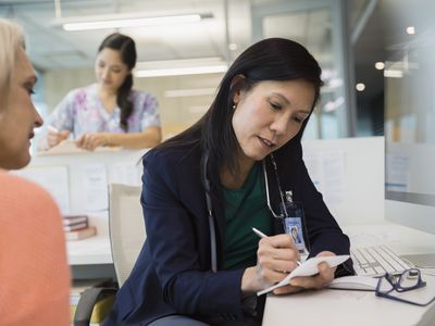 Doctor writing prescription for patient in clinic office