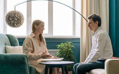 man in therapy session with a woman therapist, a big arch lamp hangs in the background