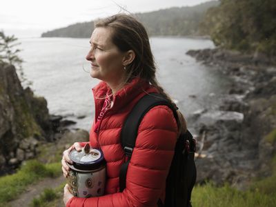 woman grieving while holding an urn by the water