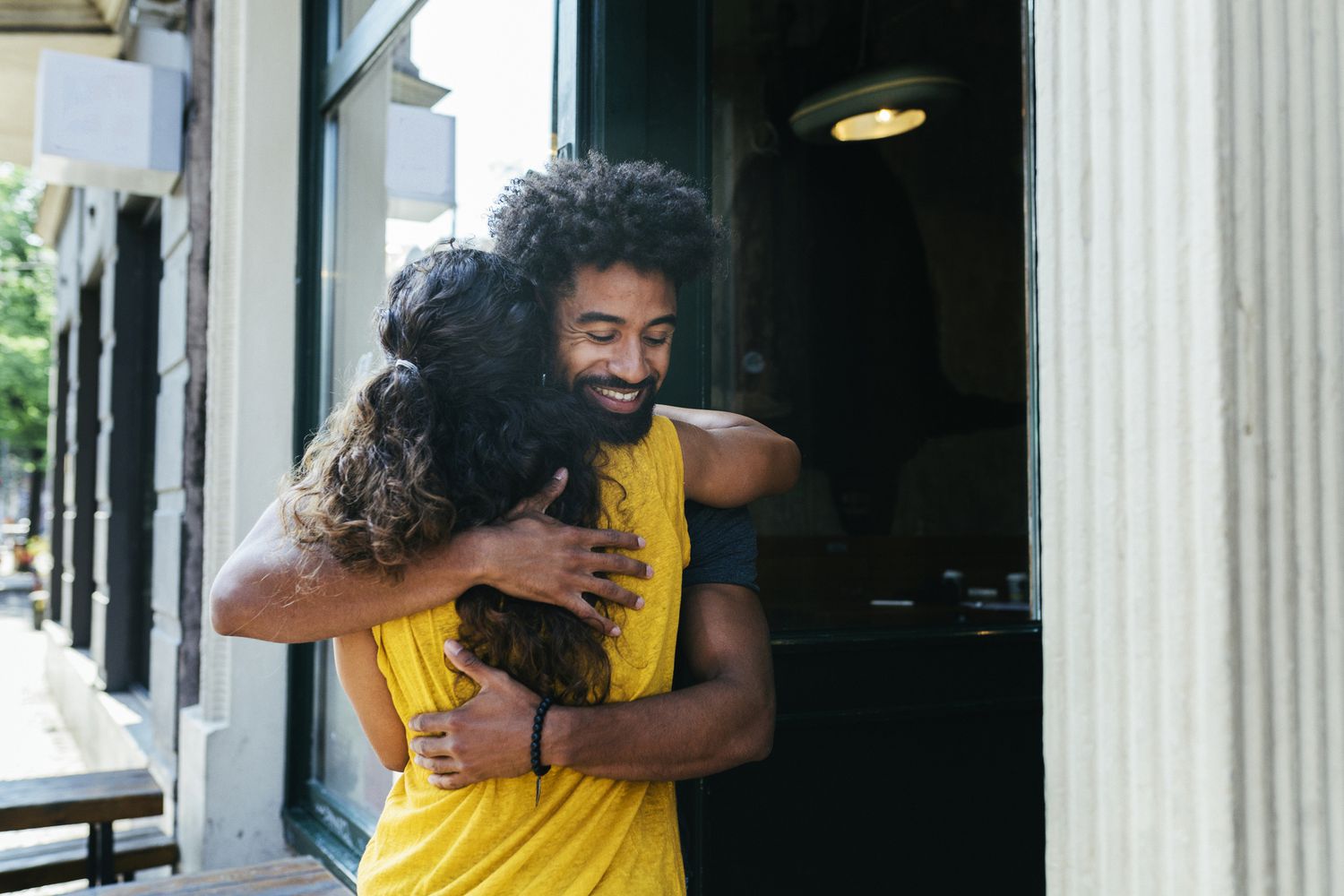 Two friends greeting each other and embracing outside a restaurant