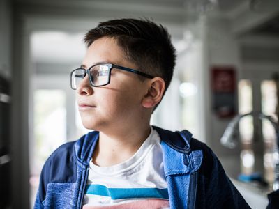 School age boy looking out window