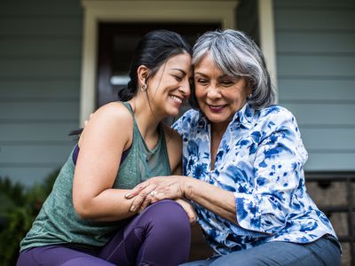 Senior woman and adult daughter laughing on porch