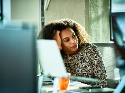 Portrait of mixed race woman looking bored at desk