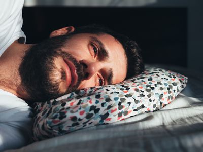 Young depressed man crying in bed