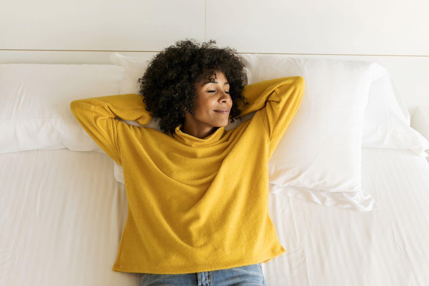 Smiling woman with closed eyes lying on bed