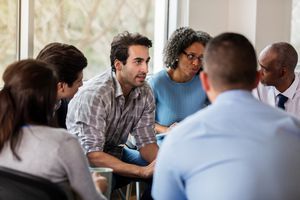 Vulnerable mid adult man talks in group therapy meeting