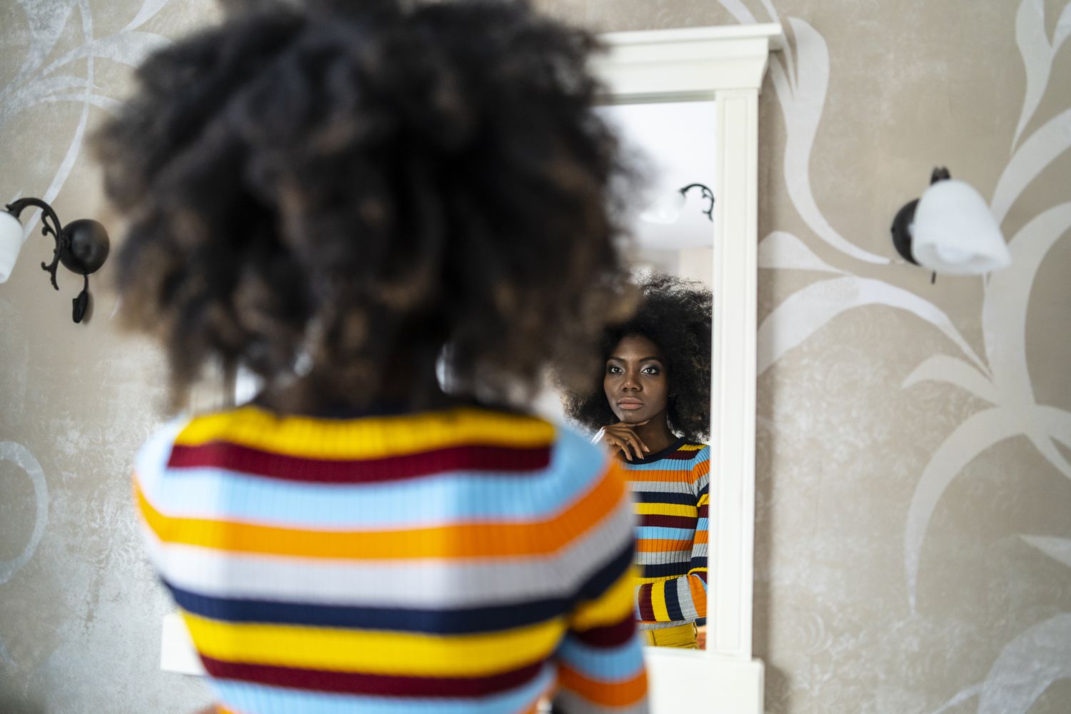 A photograph of a woman looking at her reflection in a mirror.