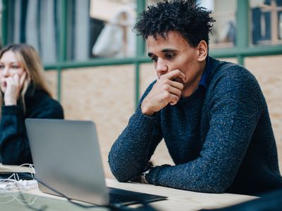 Serious worried colleagues with laptop on desk sitting in office