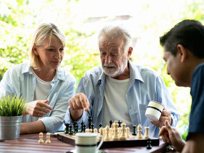 Woman and man playing chess with an older man