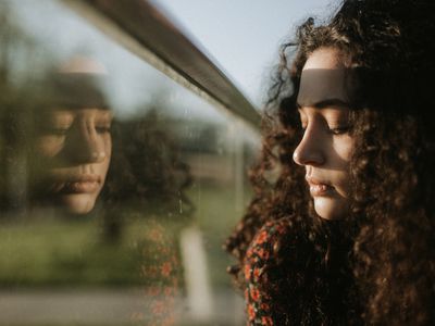 A woman with a sad expression looking out the window.