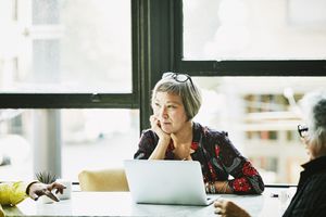 A person in front of a laptop, thinking