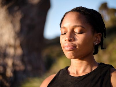 Close-up shot of healthy young woman meditating outdoors with her eyes closed