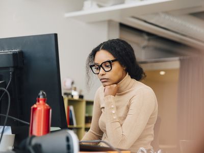 Focused computer programmer working on laptop at desk in office