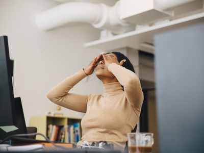 stressed woman with head in hands sitting in an office