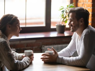 Couple sitting in cafe talking drinking tea or coffee