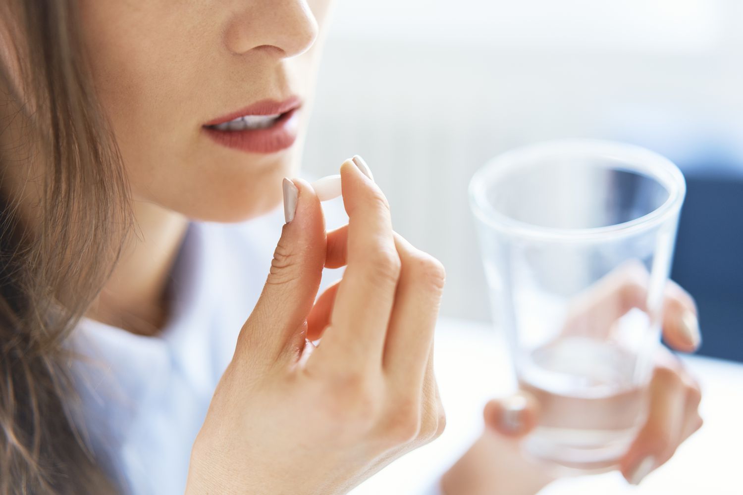 Woman taking pill with a glass of water