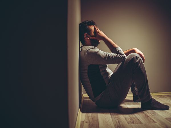 Young depressed man sitting on floor.