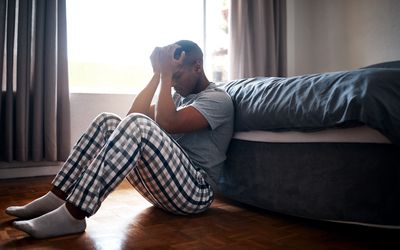 Full length shot of a handsome young man sitting at the foot of his bed and feeling depressed at home