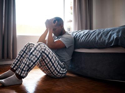 Full length shot of a handsome young man sitting at the foot of his bed and feeling depressed at home