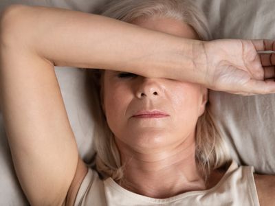 Closeup melancholic woman lying put hand on face feels unwell