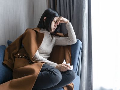 Young woman holding her nose while lying on sofa at home