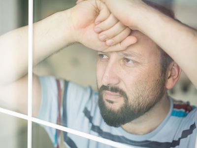 Man looking sad while looking out the window.