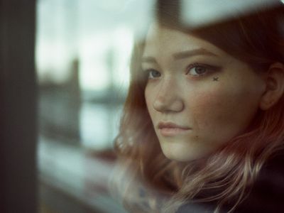 Beautiful woman stands in a parking lot and looks through a window