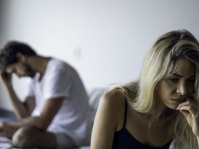 Upset couple sitting in bedroom.