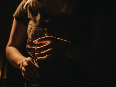 Woman holding a glass of wine in the dark