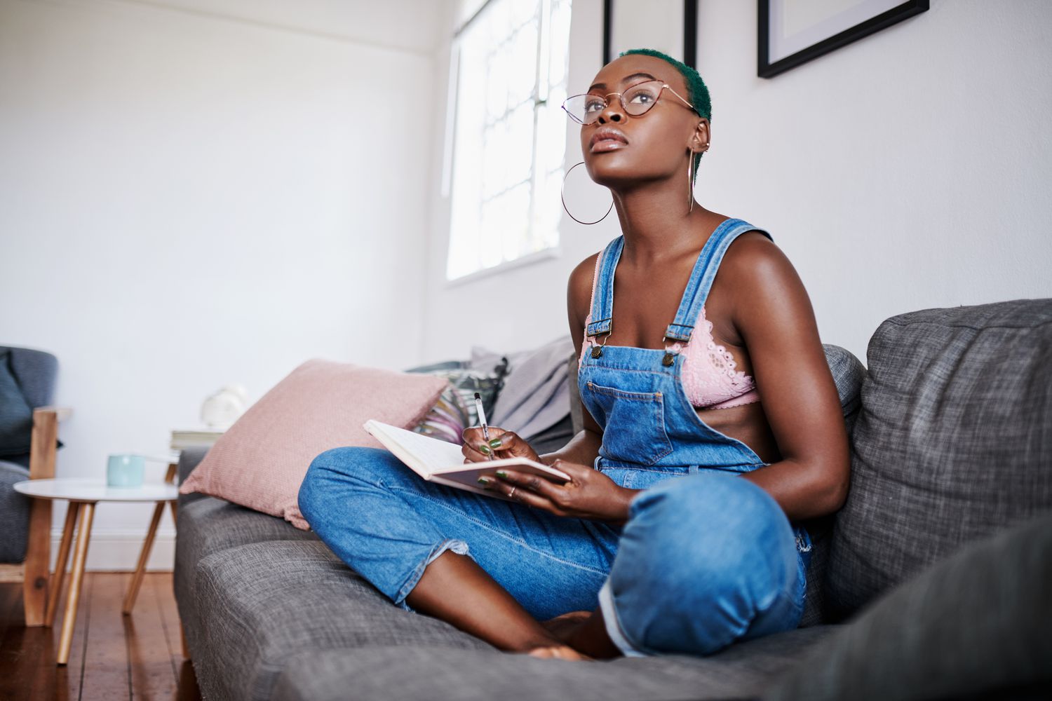 Shot of a young woman writing in a notebook while relaxing on a sofa at home