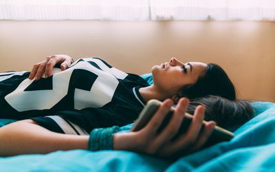 Woman lying on bed feeling depressed.