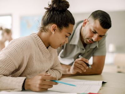 Teenager studying with professor while sitting in classroom