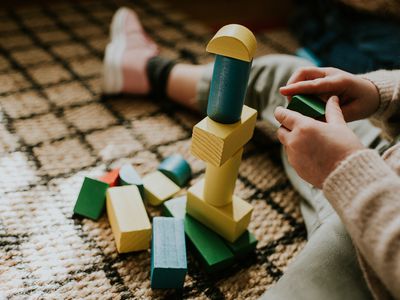 Child building coloured wooden blocks and stacking shapes.