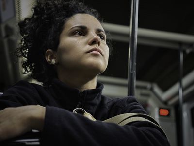 Pensive Hispanic young woman with curly hair traveling in the subway