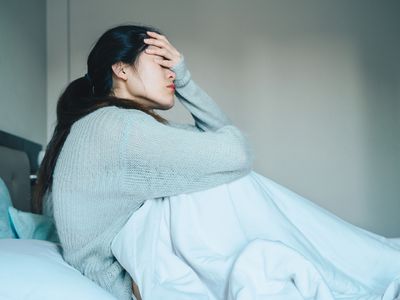 Woman in bed with head in hand.