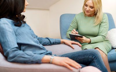 Positive blonde middle-aged woman psychologist talking to patient.