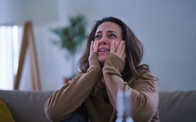 Woman crying with head in hands.