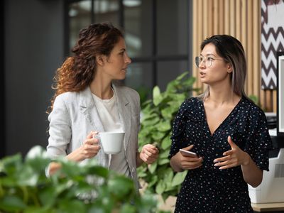 Diverse employees chatting during coffee break in modern office